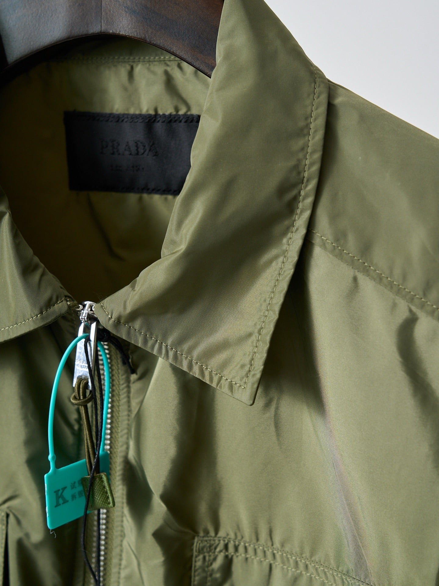 Olive green Prada jacket sleeve cuff with drawstring and turquoise tag detail