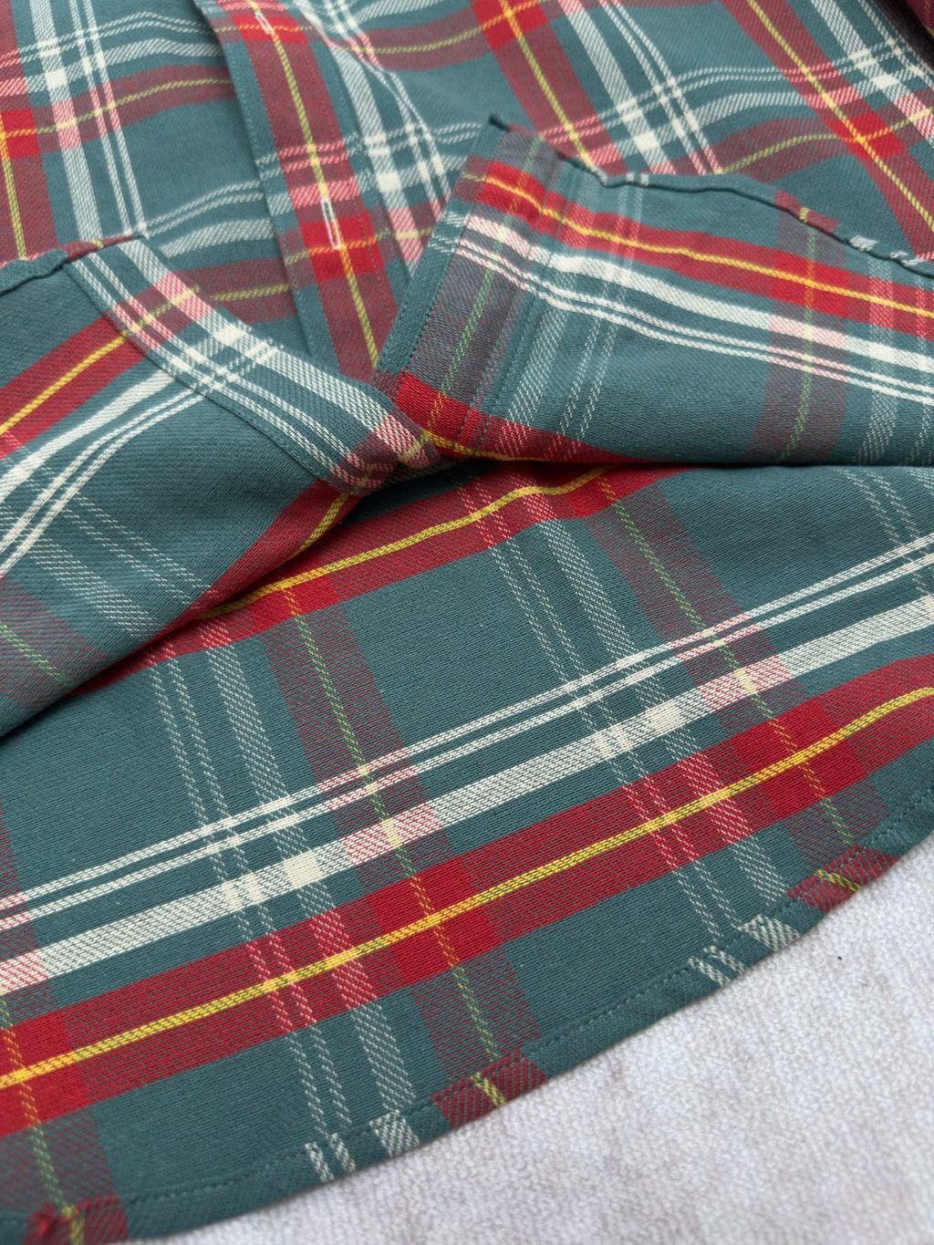 Teal plaid shirt sleeve with stitched seam and colorful plaid pattern