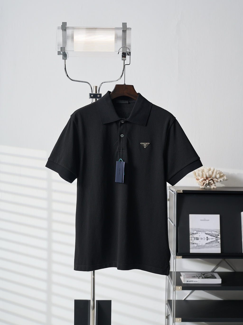 Black Prada polo shirt with short sleeves and button placket on hanger