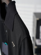 Side view of black Prada polo sleeve with textured fabric and logo stud