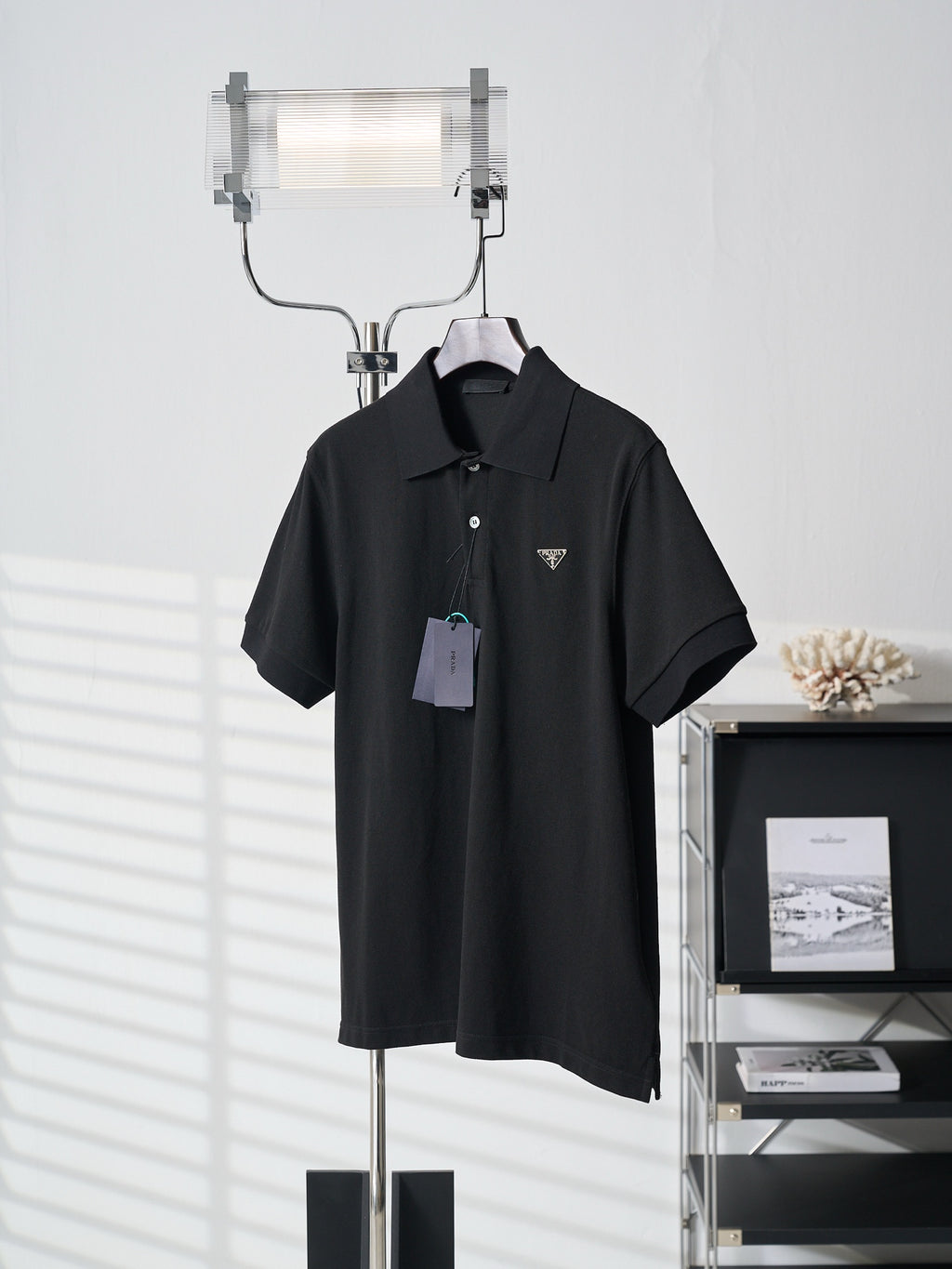 Black Prada polo shirt with triangle logo and hang tag on hanger