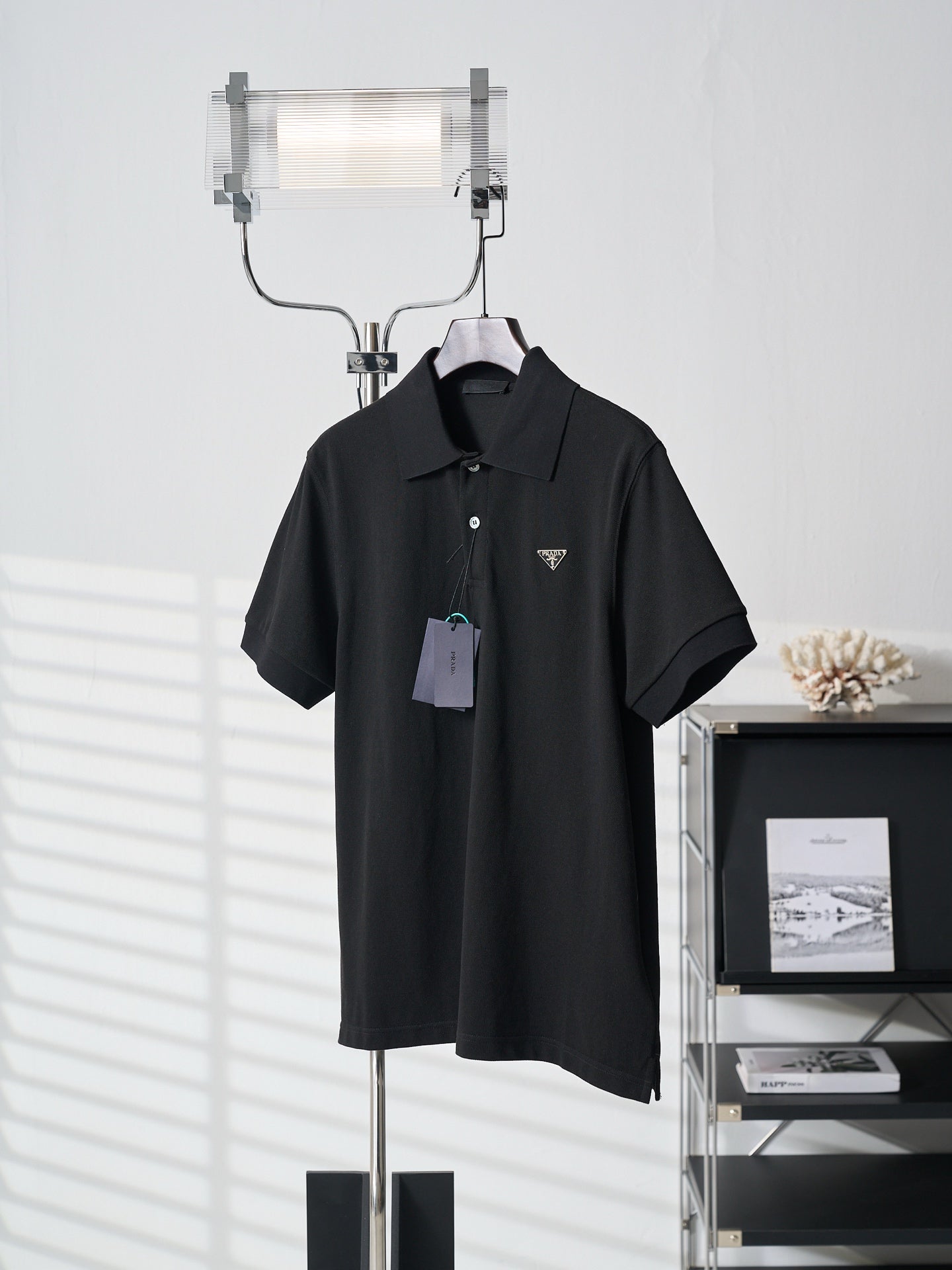 Black Prada polo shirt with triangle logo and hang tag on hanger