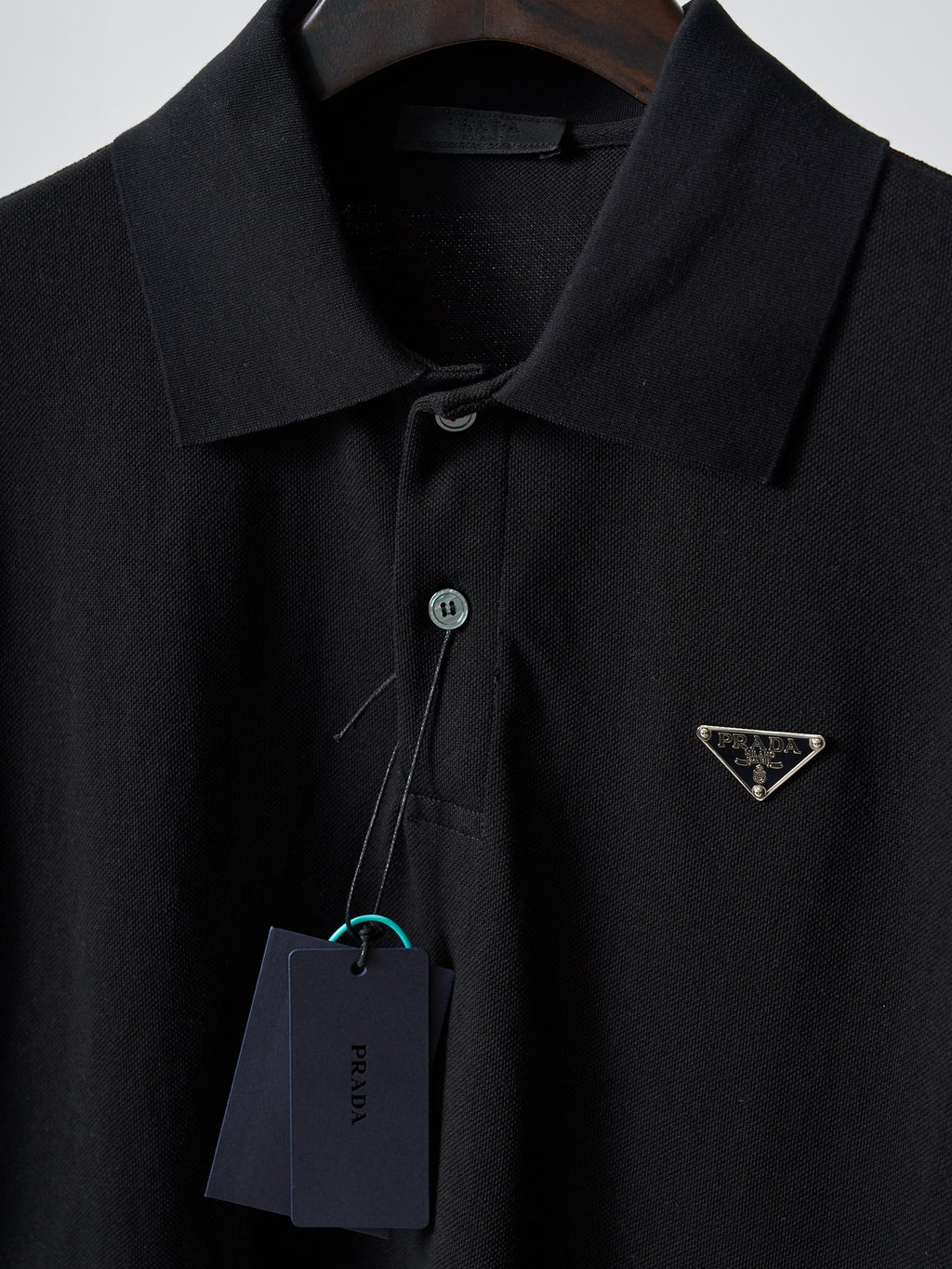 Close-up of black Prada polo collar with button placket and triangle logo