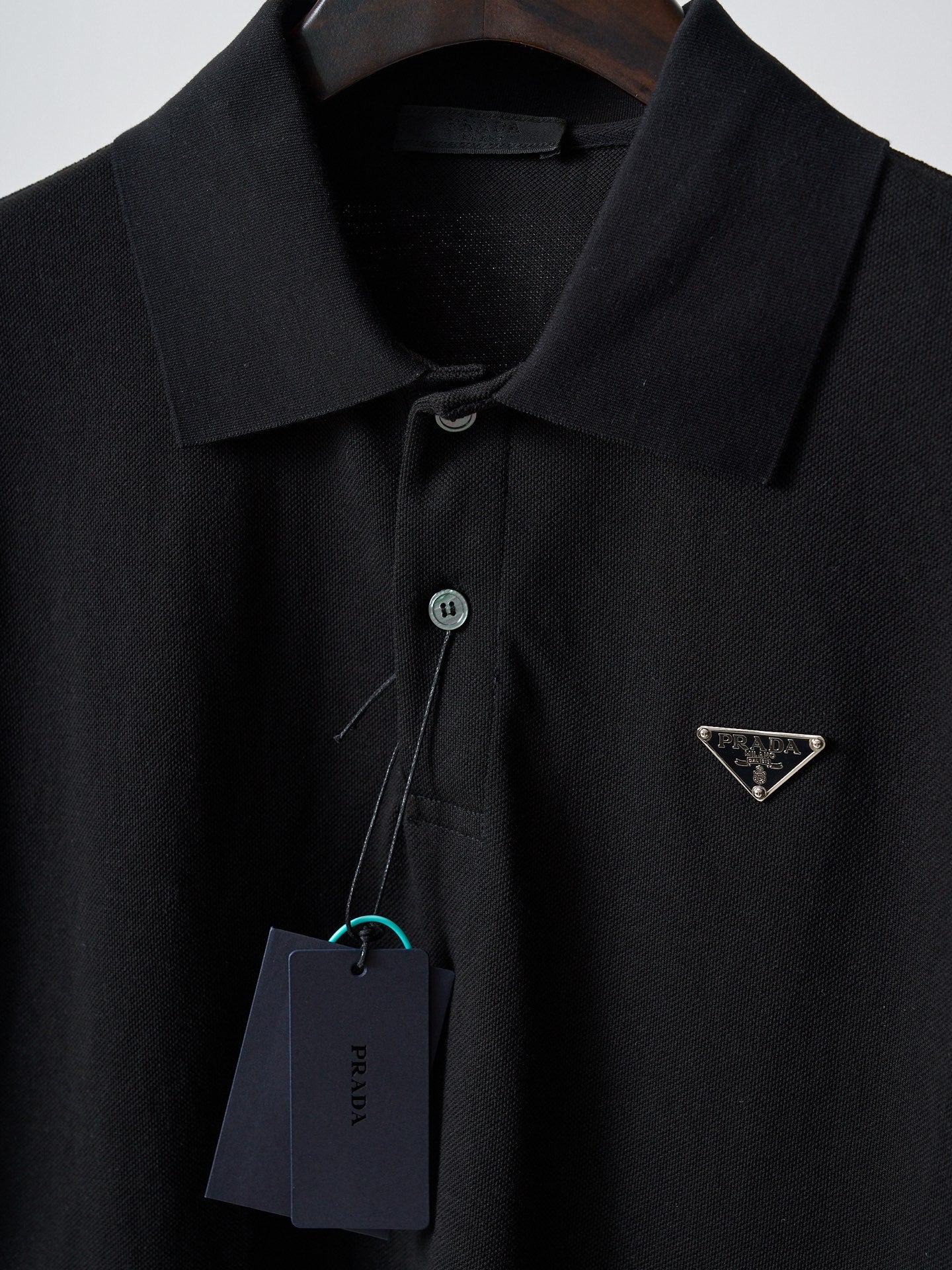 Close-up of black Prada polo collar with button placket and triangle logo