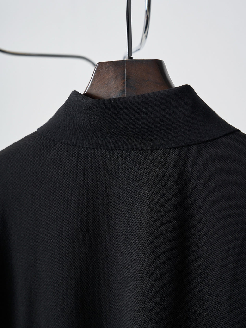 Back yoke of black polo shirt on hanger with fabric texture