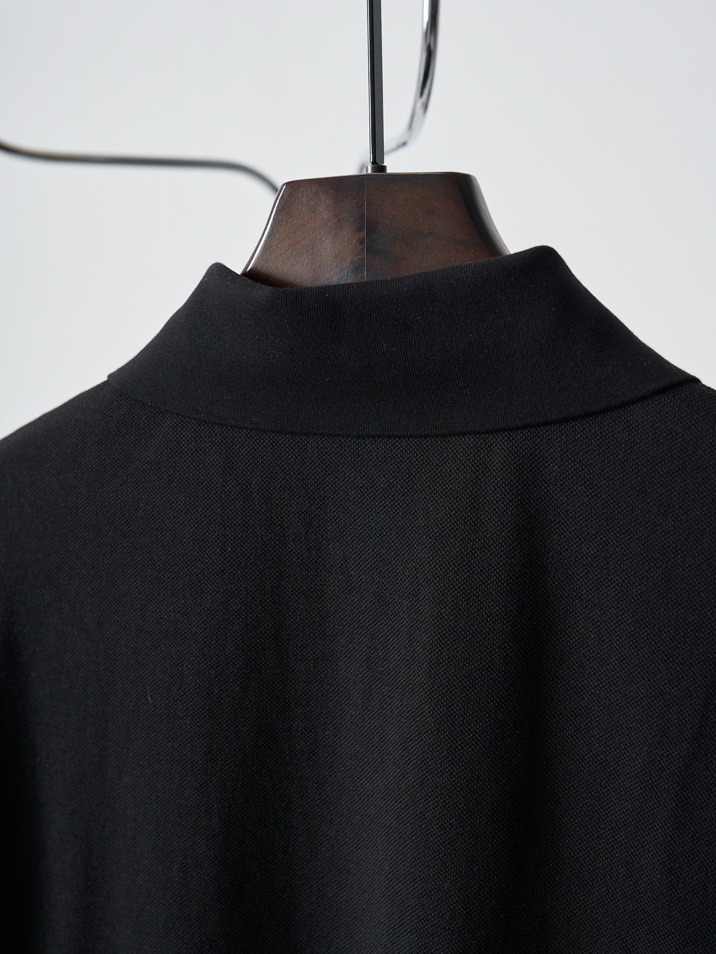 Back yoke of black polo shirt on hanger with fabric texture