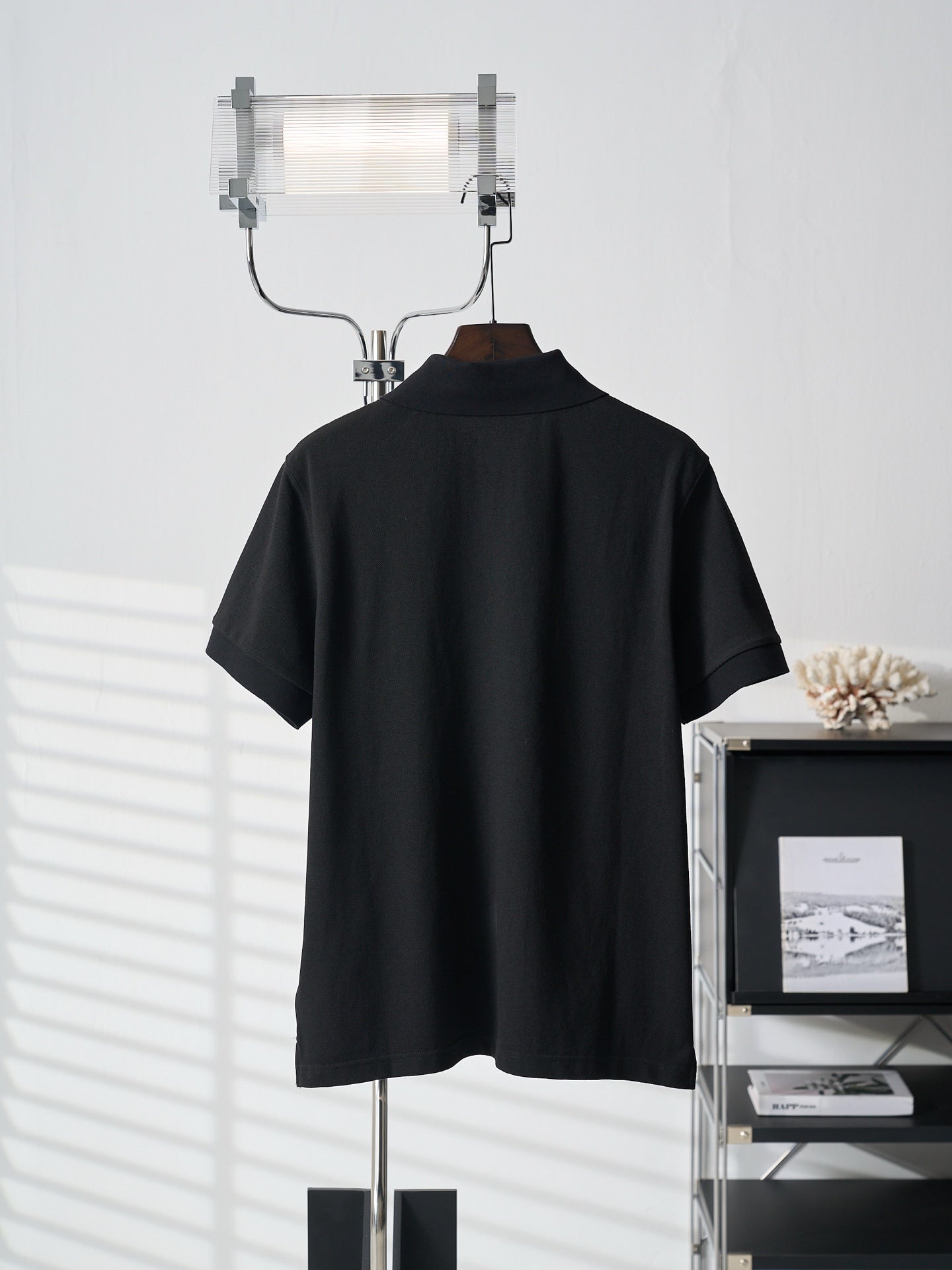 Black Prada polo shirt with stand collar and short sleeves on hanger
