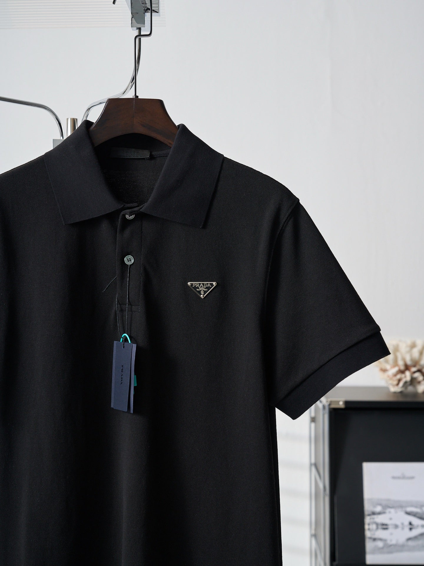 Black Prada polo shirt front view with hang tag on wooden hanger