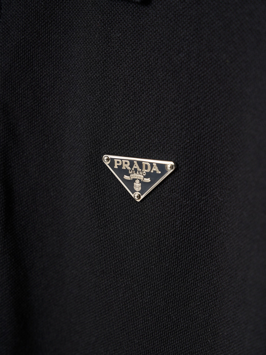 Triangle Prada logo patch on dark polo fabric