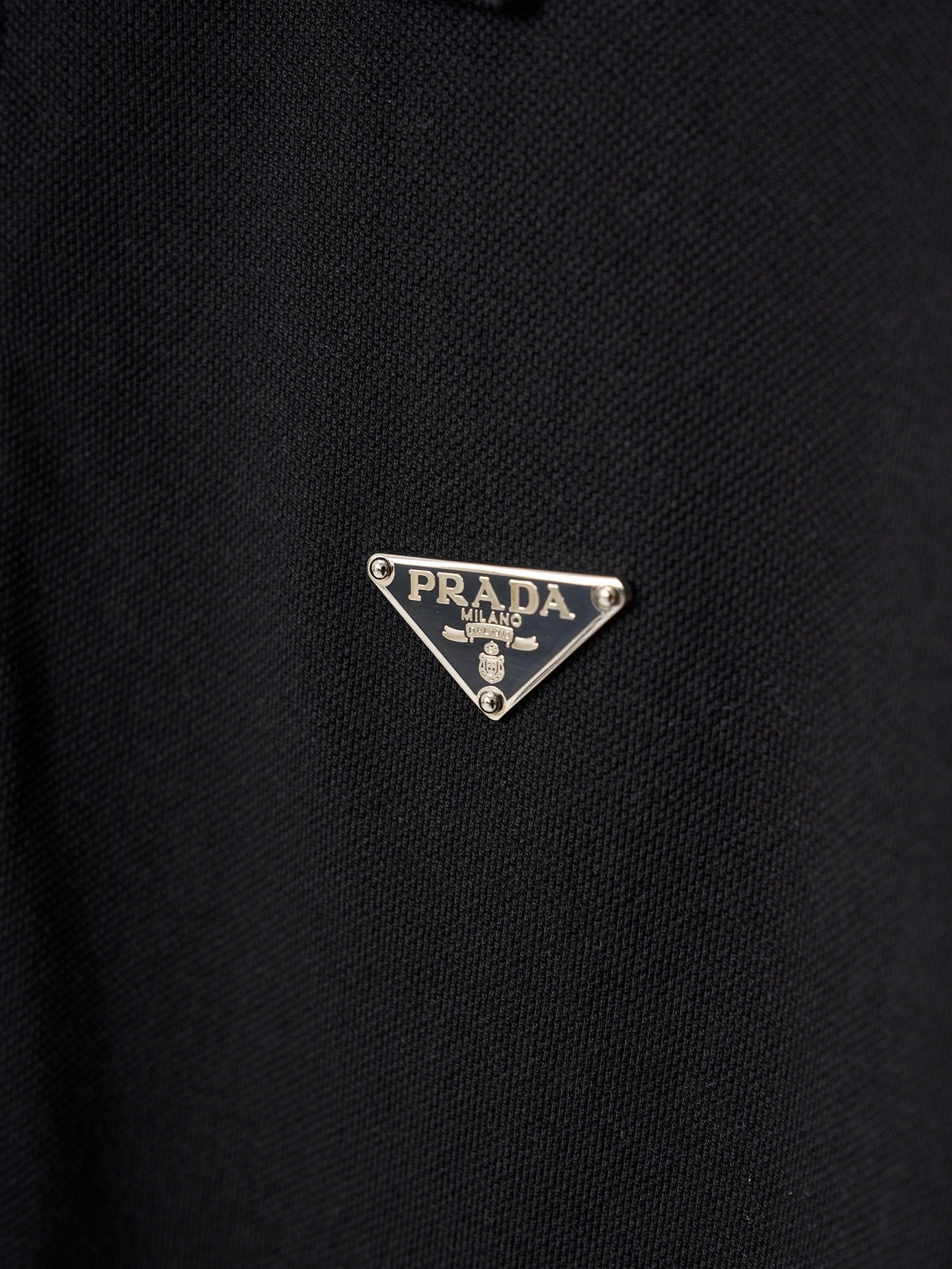 Triangle Prada logo patch on dark polo fabric