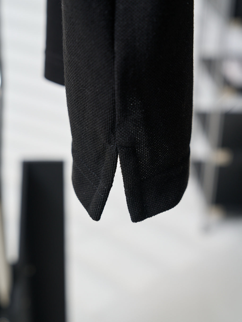 Close-up of black polo shirt hem and side seam