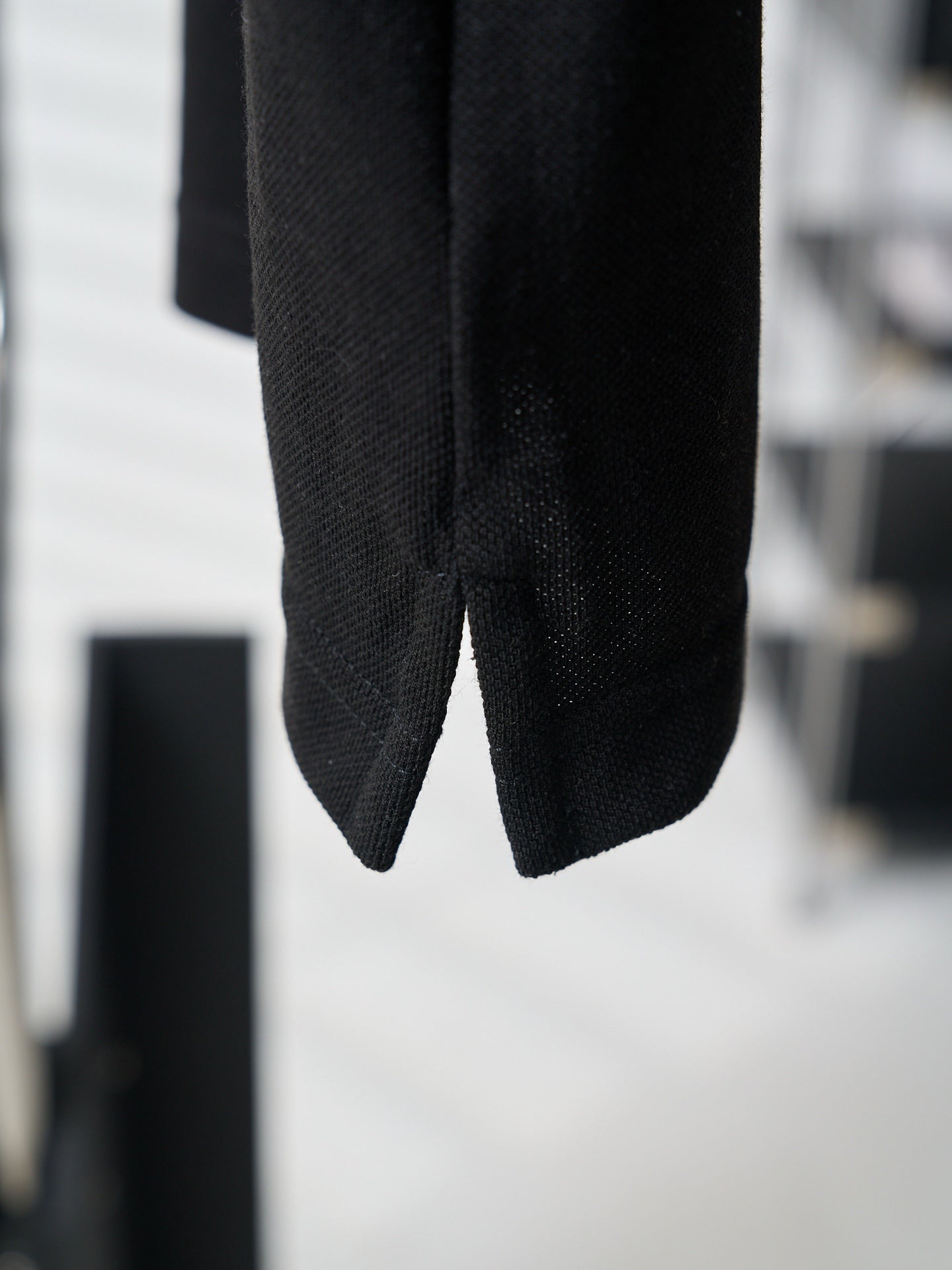 Close-up of black polo shirt hem and side seam