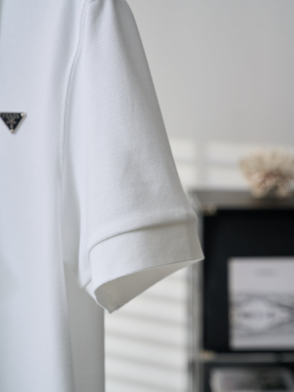 White polo shirt sleeve with embroidered PRADA logo, side view