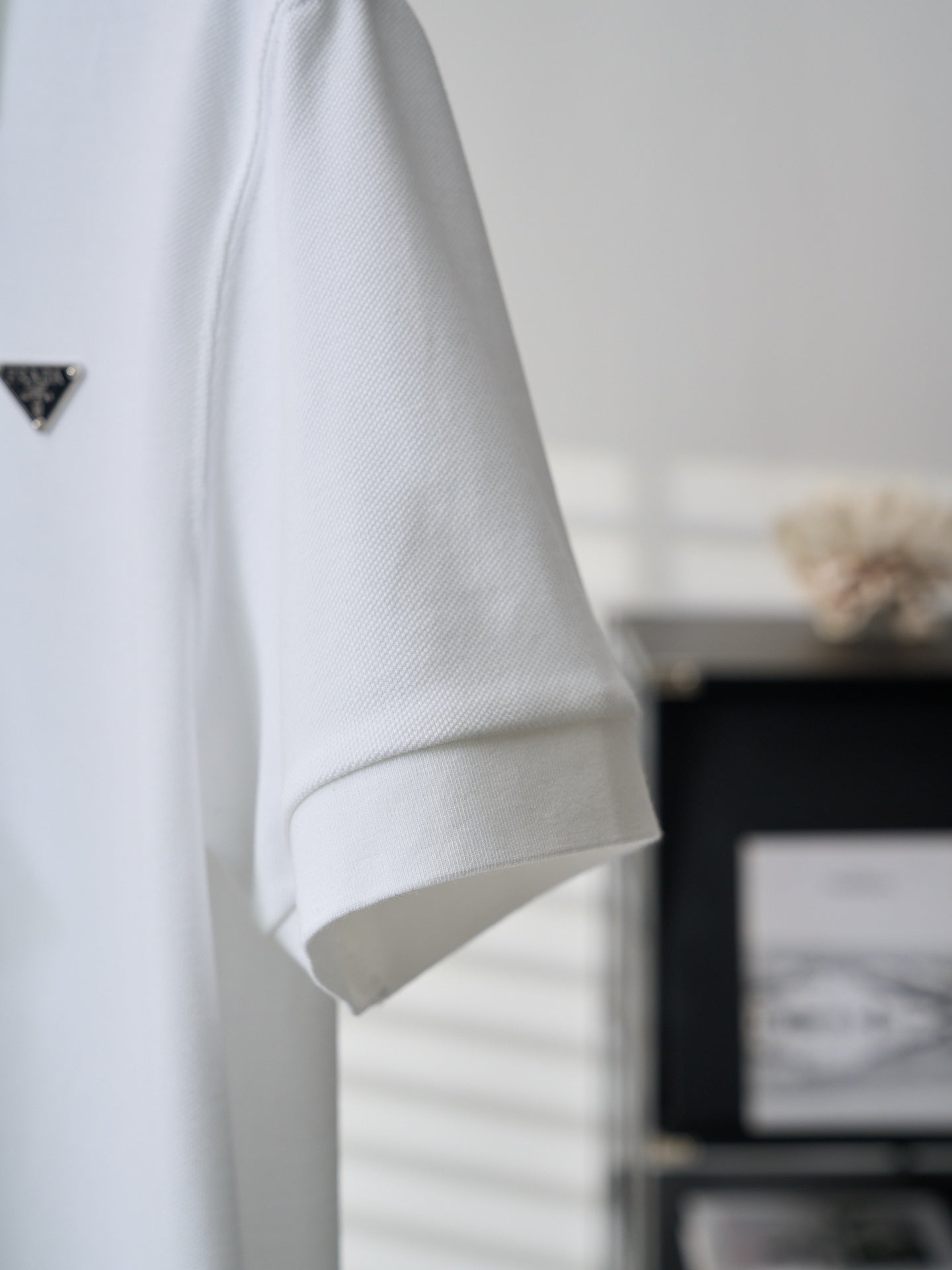 White polo shirt sleeve with embroidered PRADA logo, side view