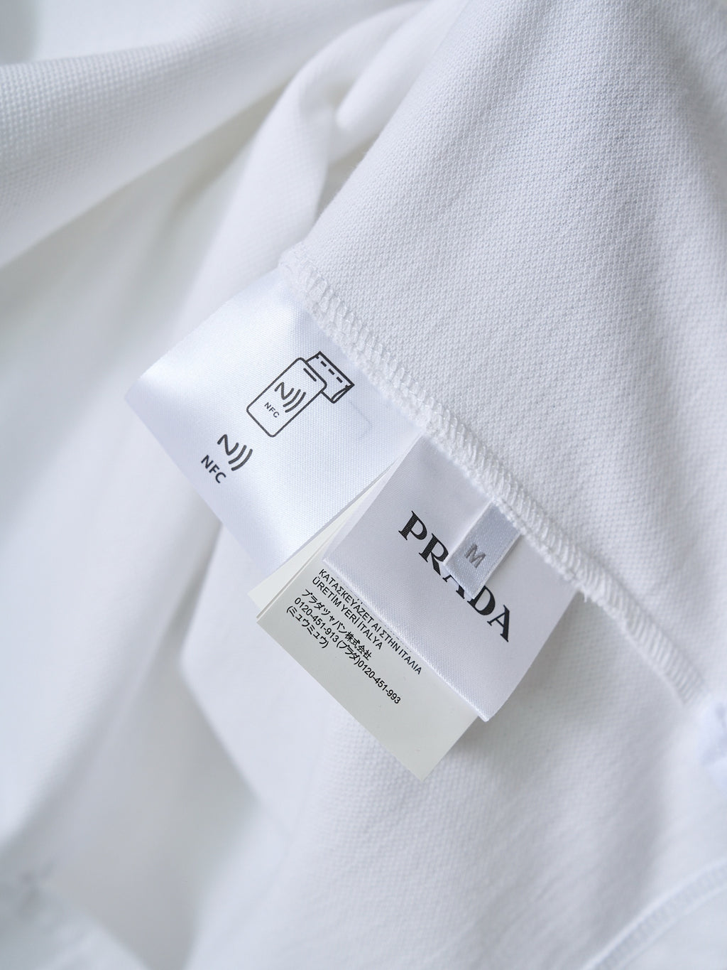 Care label and PRADA tag on white polo shirt interior seam