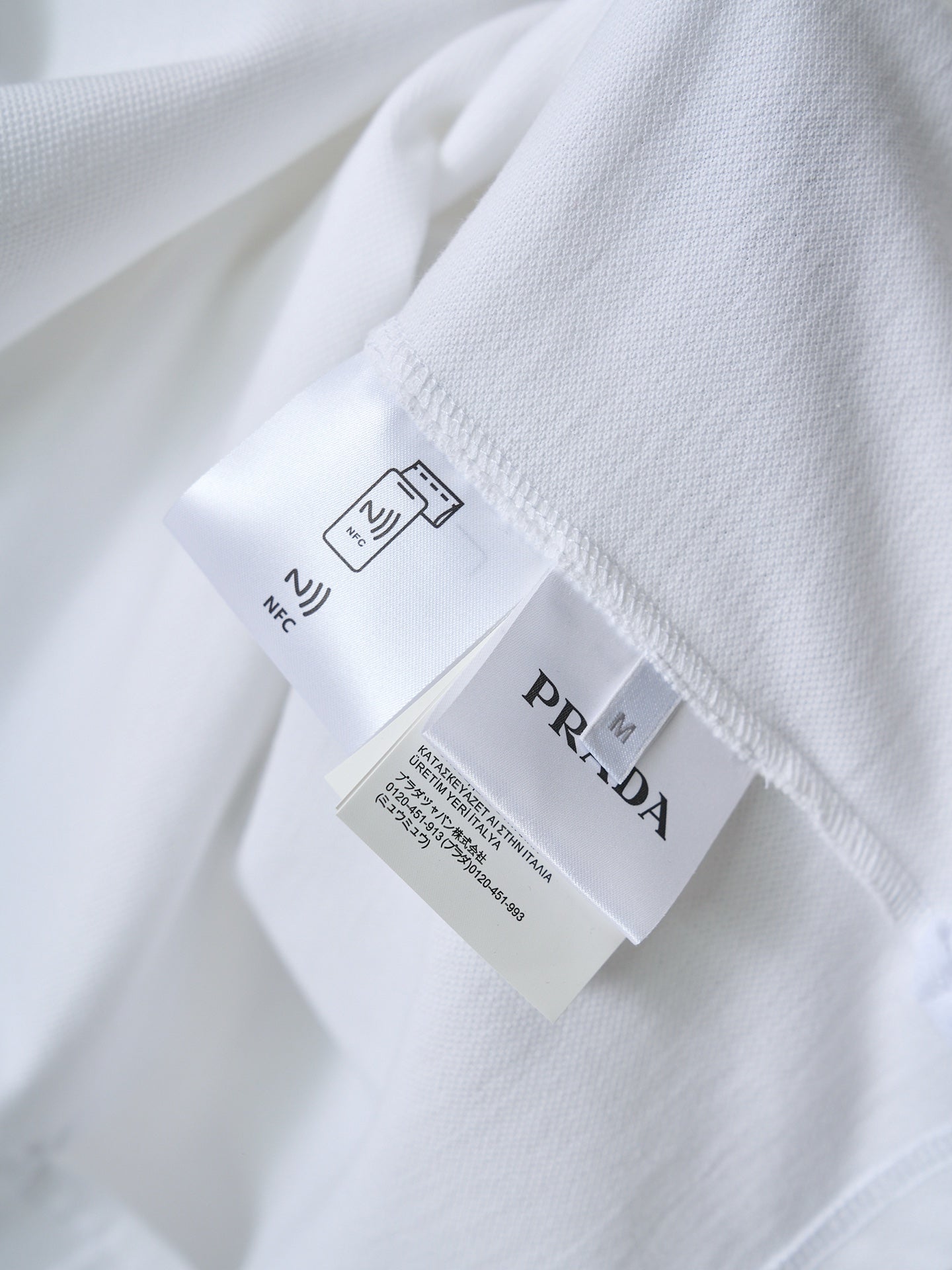 Care label and PRADA tag on white polo shirt interior seam