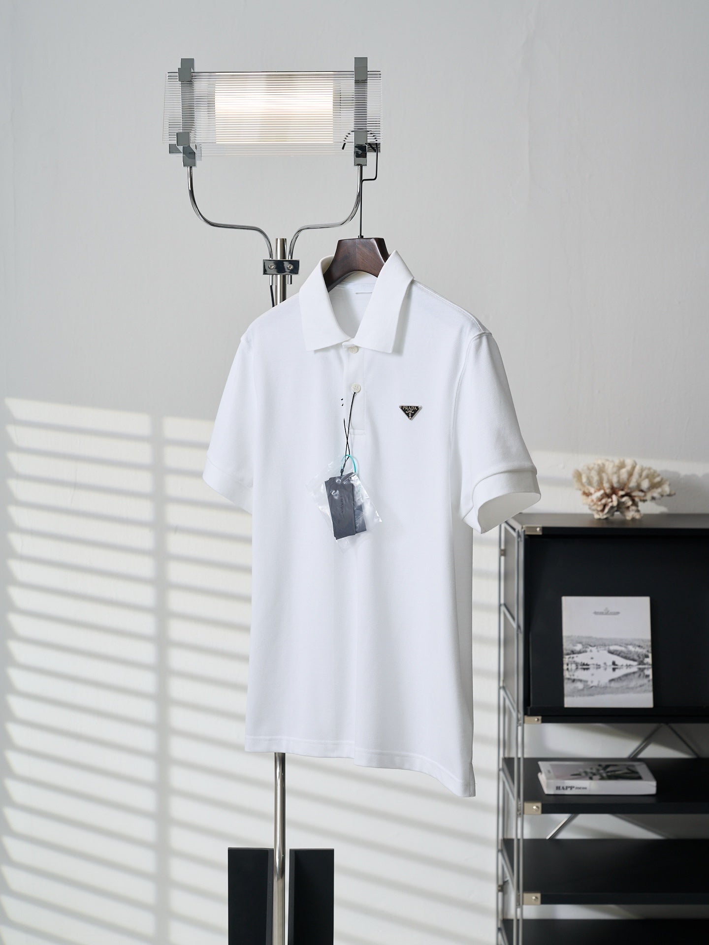 White short-sleeve polo shirt with collar and PRADA logo patch, front view