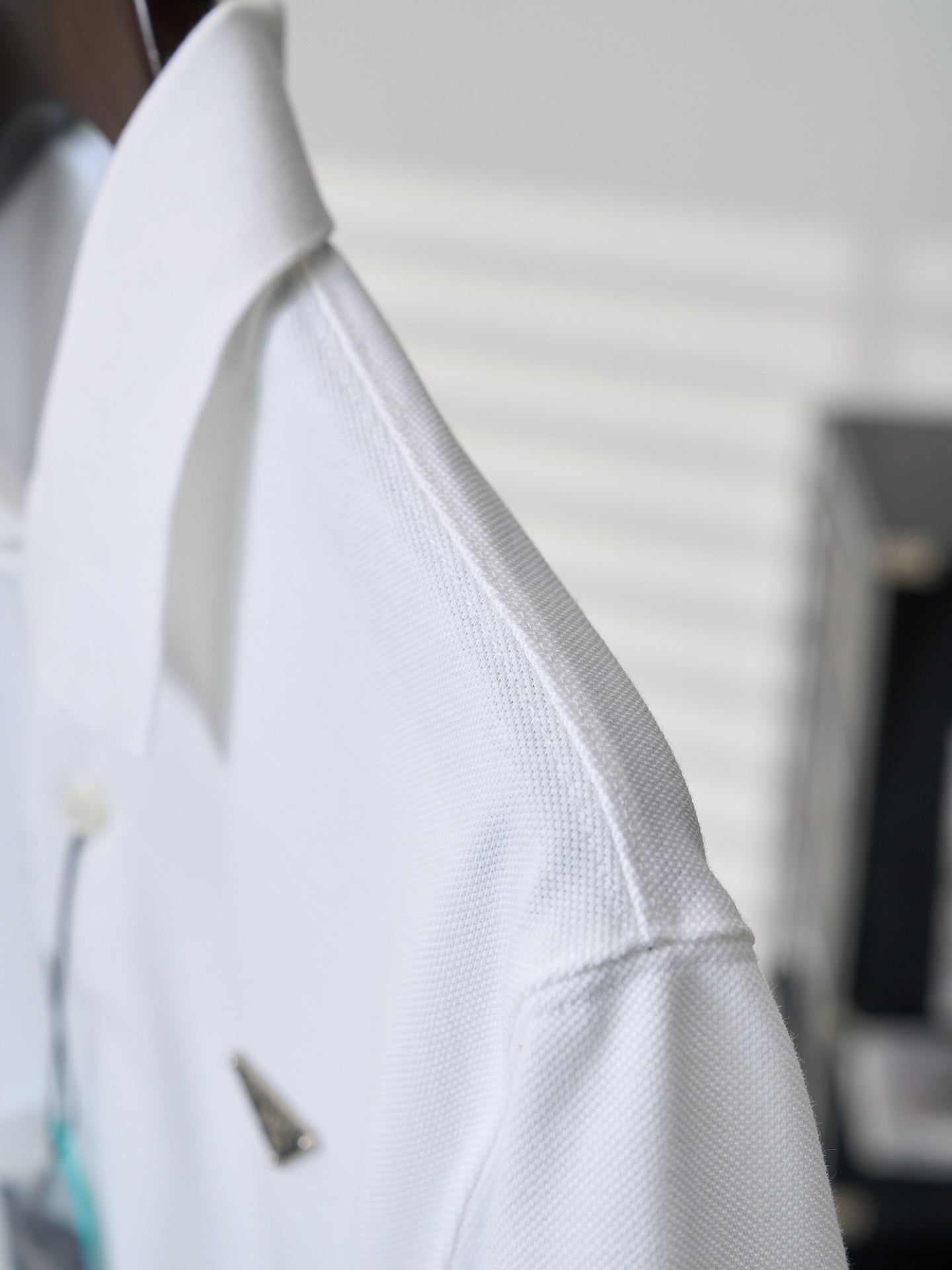 White polo shirt sleeve with textured fabric and small logo detail