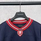 Balenciaga navy sweatshirt with ribbed striped collar and crest emblem at center neck