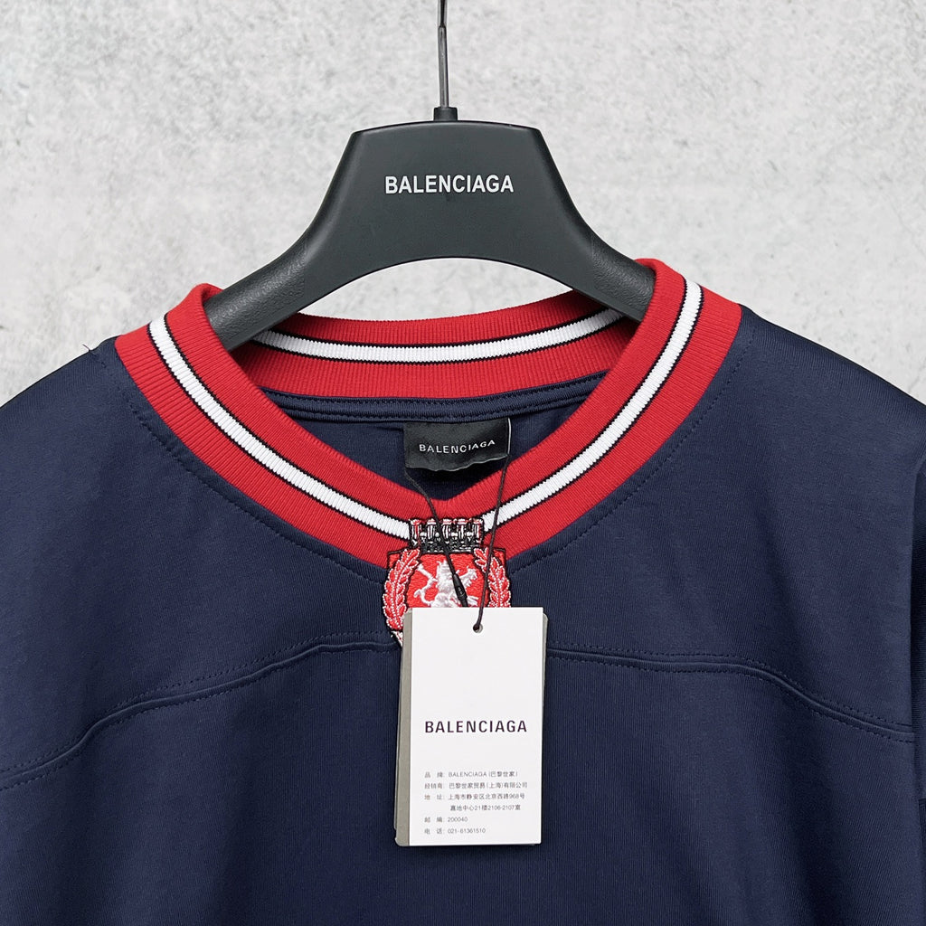 Balenciaga navy sweatshirt neckline with red-and-white striped collar and crest emblem