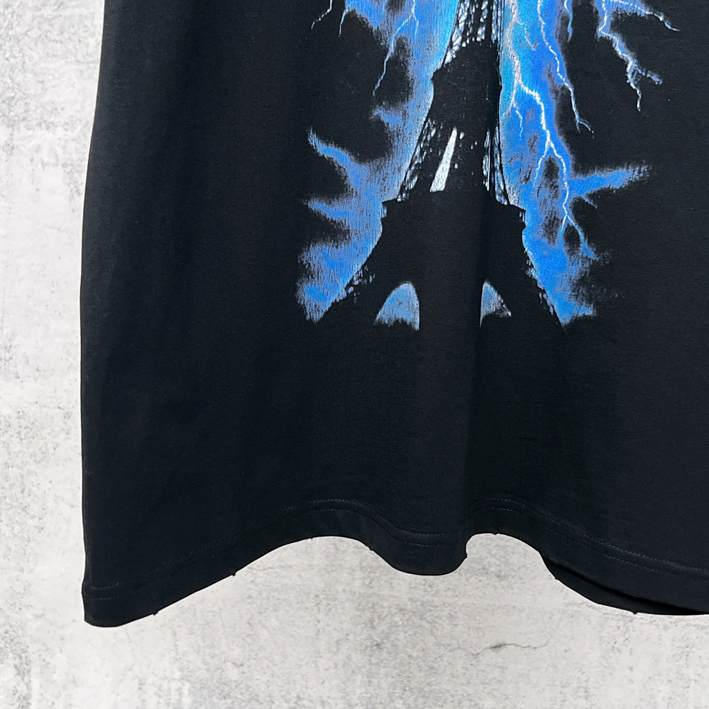 Black T-shirt hem with blue lightning Eiffel graphic near bottom