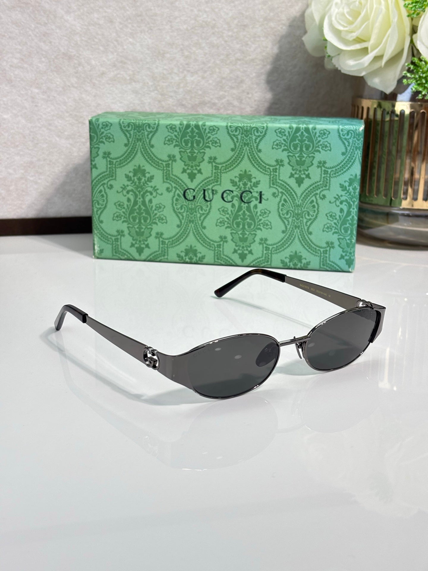 Gucci sunglasses with dark lenses and silver-tone frame, cat-eye oval silhouette