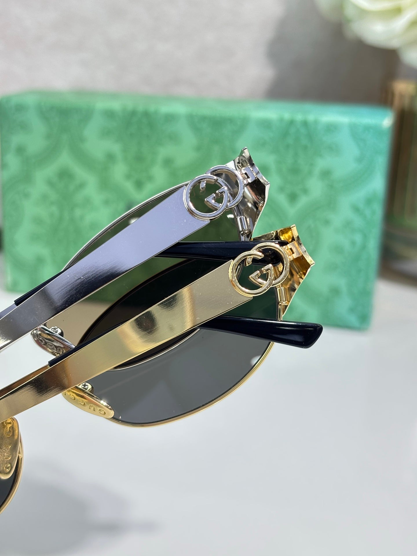 Gucci sunglasses close-up of gold and silver-tone hinges with logo accents
