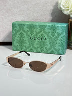 Gucci sunglasses with brown lenses and gold-tone frame, rounded oval shape