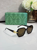 Gucci sunglasses with black square frames and brown tinted lenses, gold logo bridge