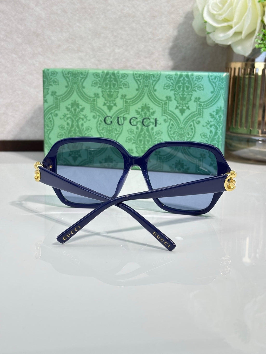 Gucci sunglasses with navy square frames and blue-tinted lenses, gold logo detail