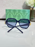 Gucci sunglasses with navy square frames and blue-tinted lenses, gold logo detail