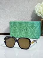Gucci sunglasses with black square frames and brown tinted lenses, gold logo detail