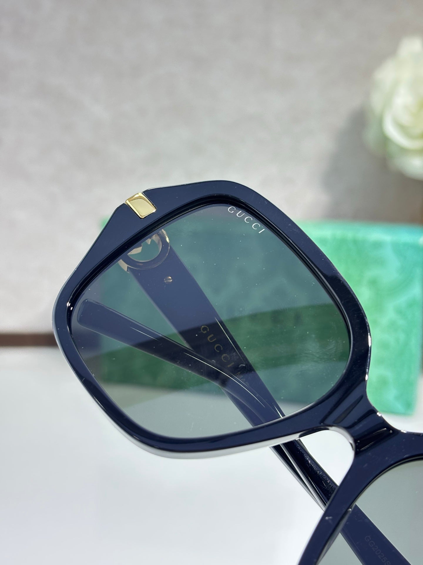Gucci sunglasses lens close-up with navy frames and Gucci logo on temple