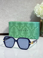 Gucci sunglasses with navy square frames and light tinted lenses, gold logo detail
