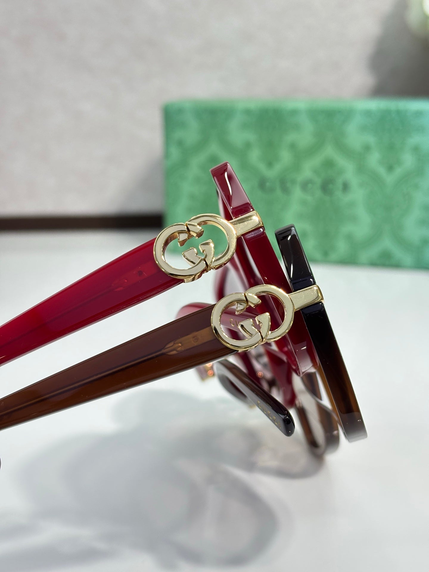 Gucci sunglasses close-up: red acetate frames with gold logo bar and hinge hardware