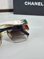 Chanel sunglasses closeup with black lenses, gold trim, white temples