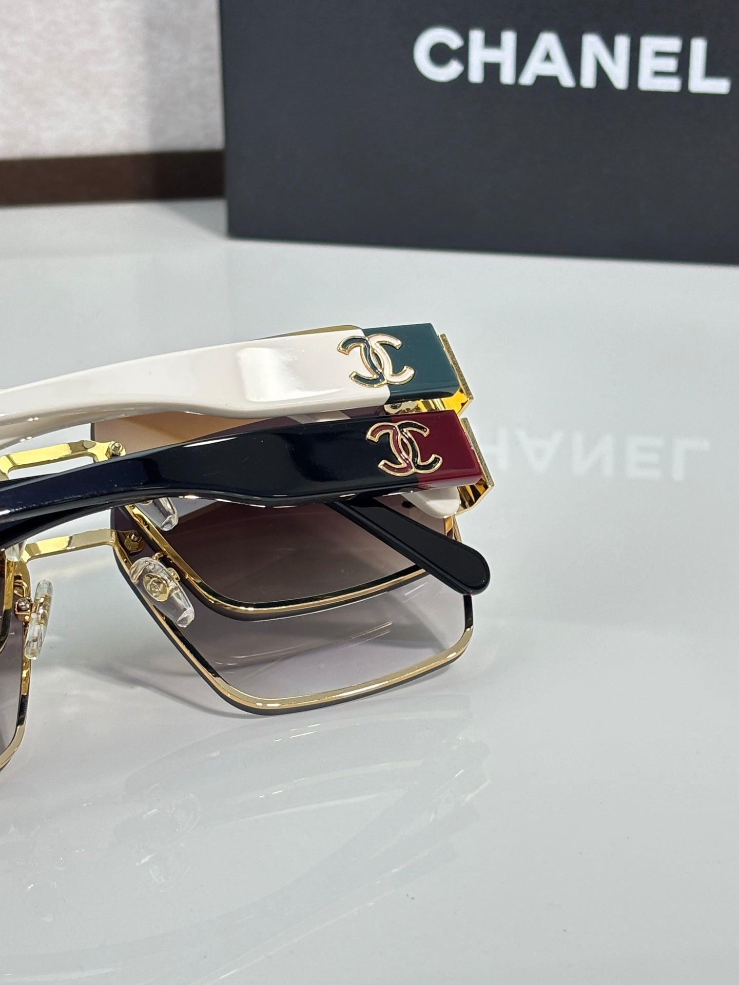 Chanel sunglasses closeup with black lenses, gold trim, white temples