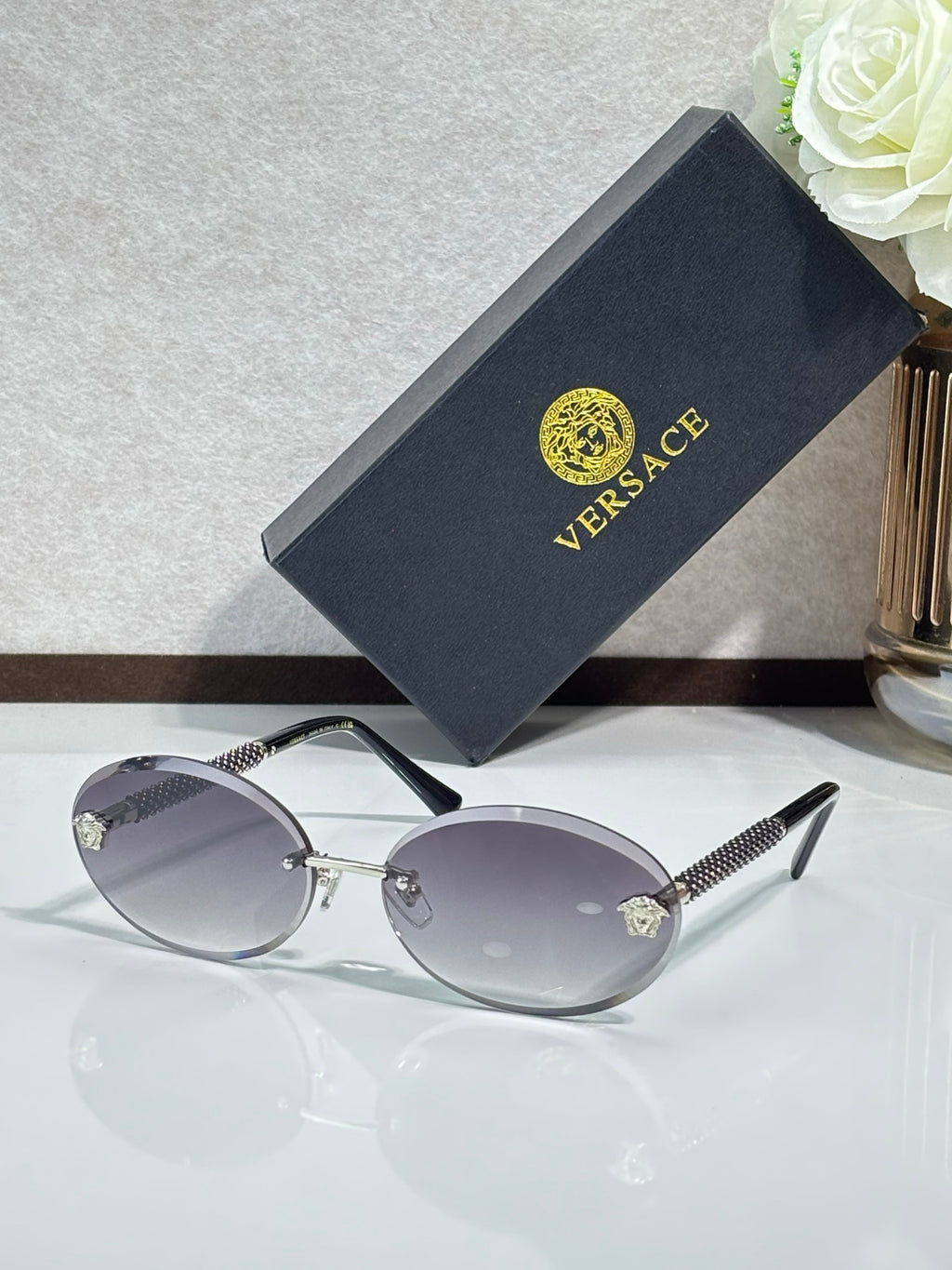 Versace sunglasses: round dark frames, silver-tone temples, gray tinted lenses.