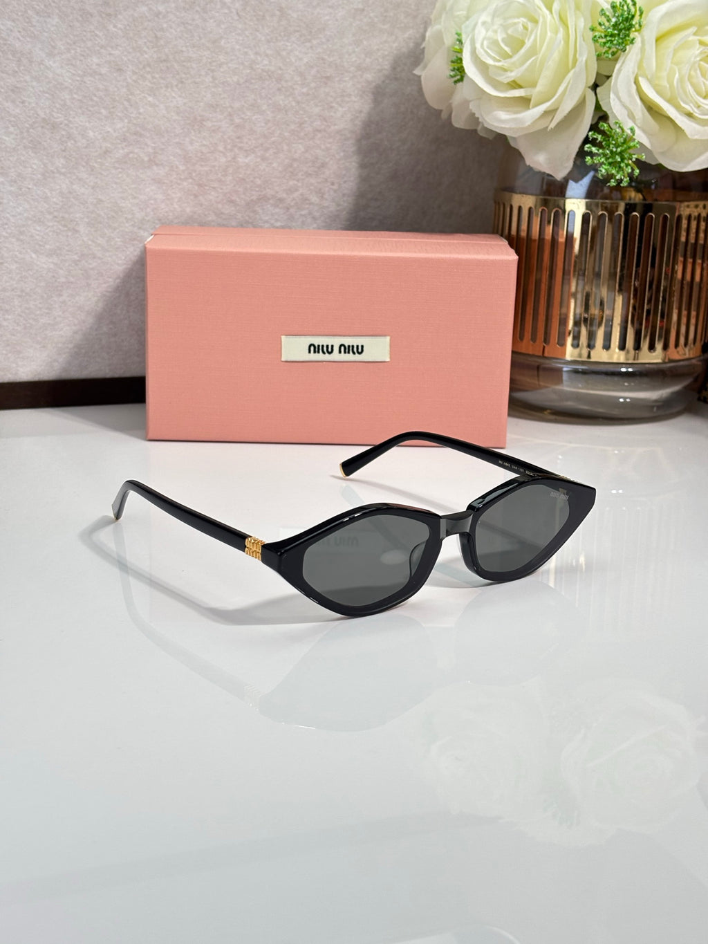 Black cat-eye sunglasses with dark lenses and gold-tone chain-style temple detail