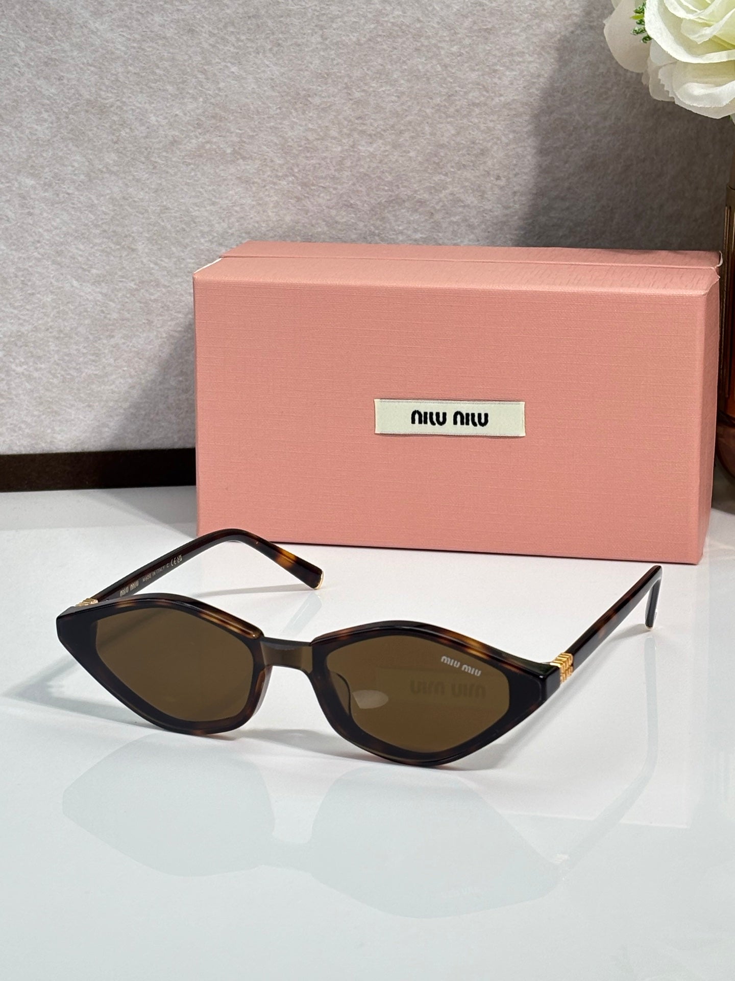 Black cat-eye sunglasses with dark lenses and gold-tone temple accents