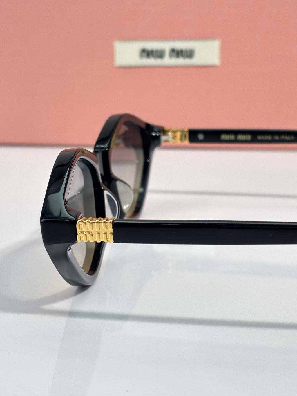 Black cat-eye sunglasses close-up with gold-tone emblem on the temple