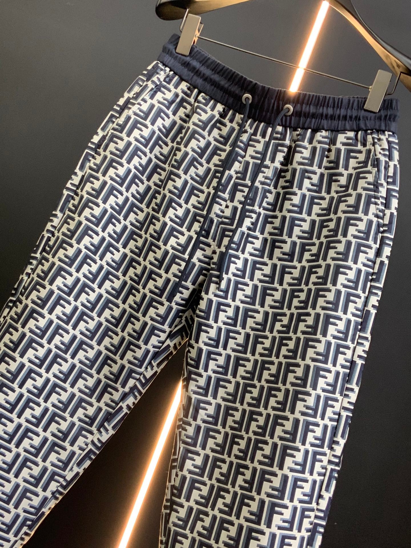 Black pants with white FF-style repeating pattern and ribbed elastic waistband, close-up