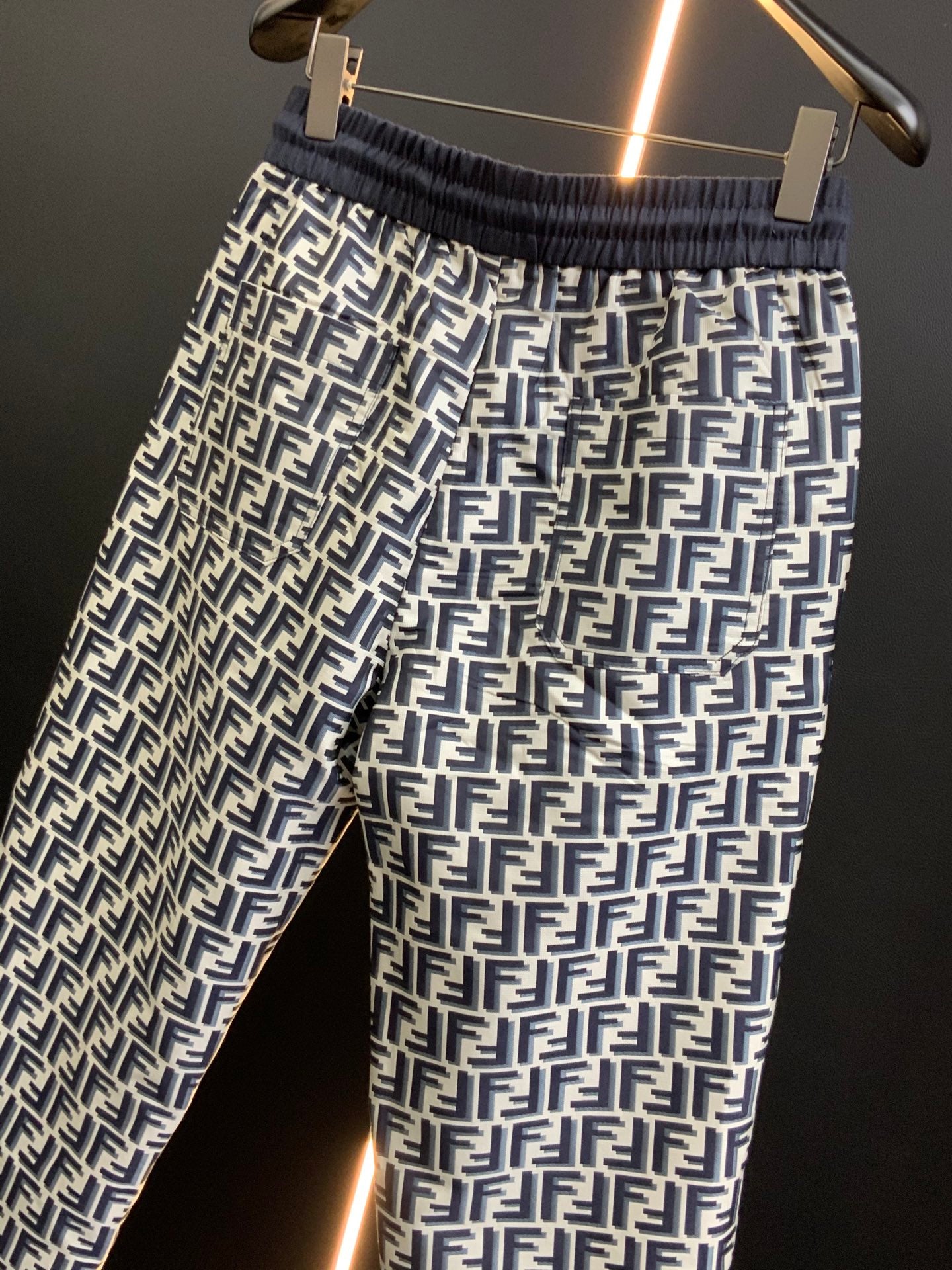 Black pants with white FF-style repeating pattern and elastic waistband, front close-up