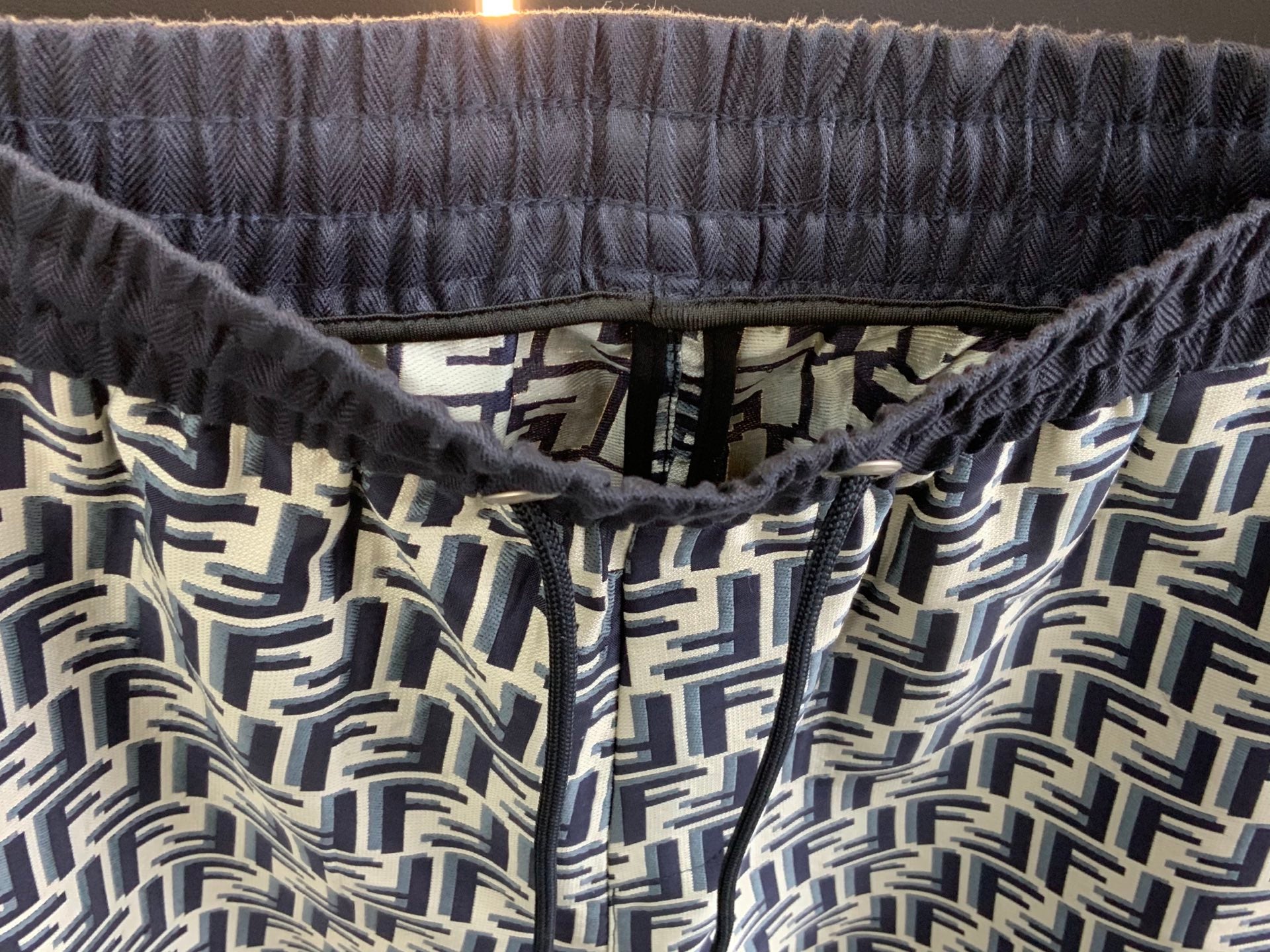 Elastic waistband with drawstring and FF-style repeating pattern, close-up