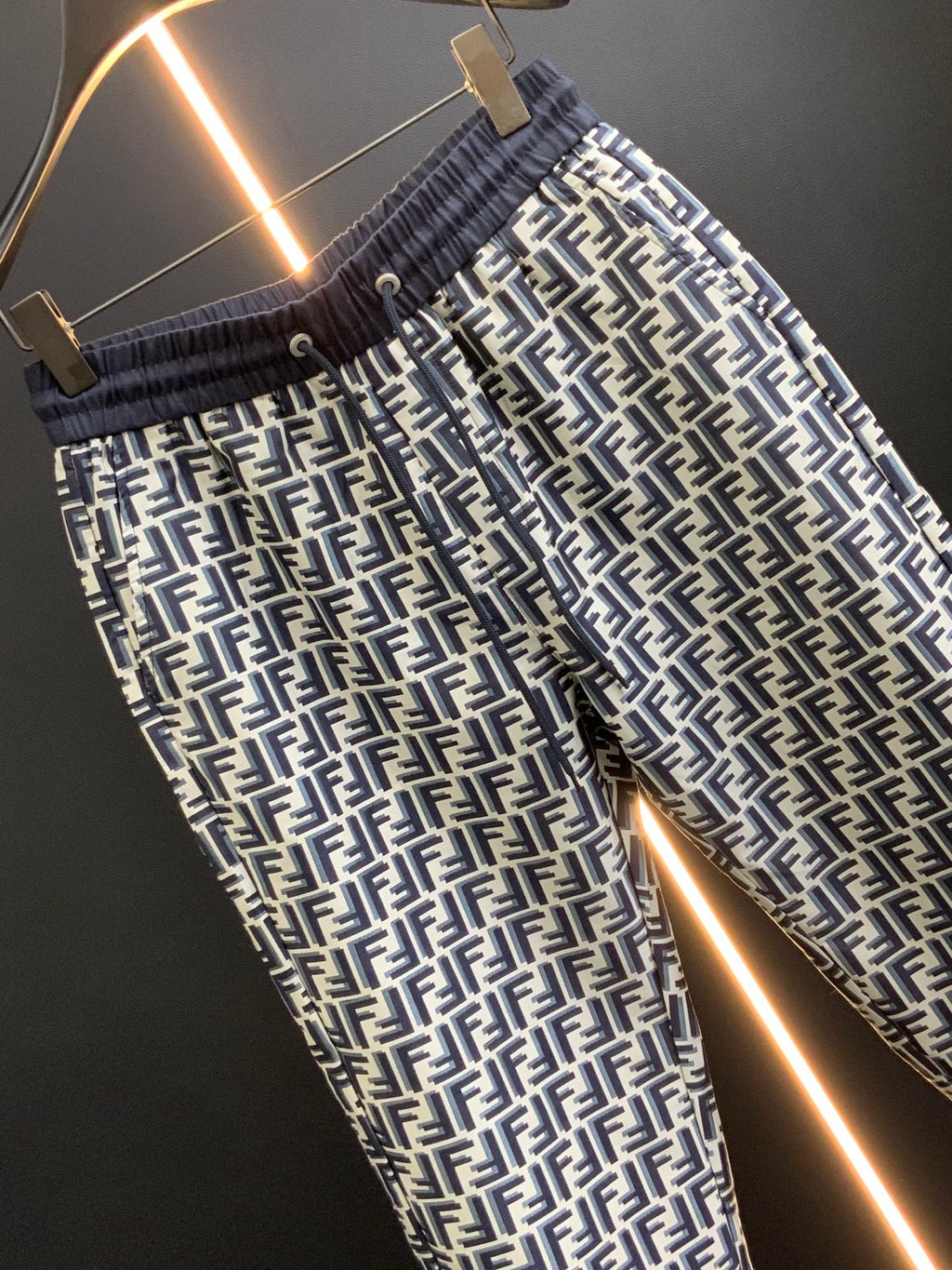 Black pants with white FF-style repeating pattern and elastic waist, angled close-up