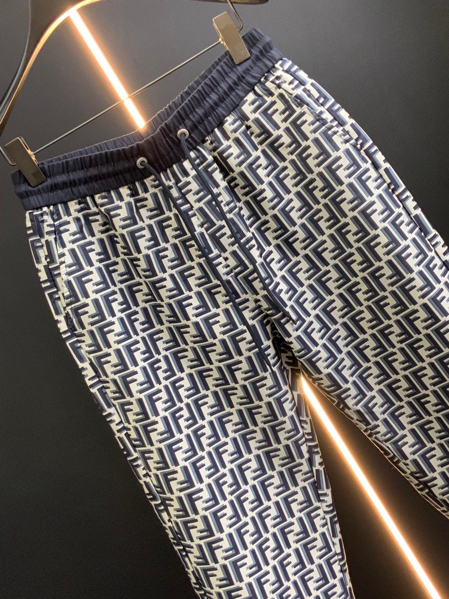 Black pants with white FF-style repeating pattern and elastic waist, angled close-up