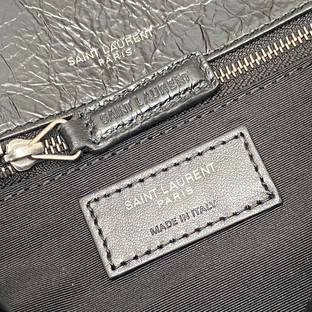 Saint Laurent leather bag close-up: zipper, brand print, and Made in Italy tag
