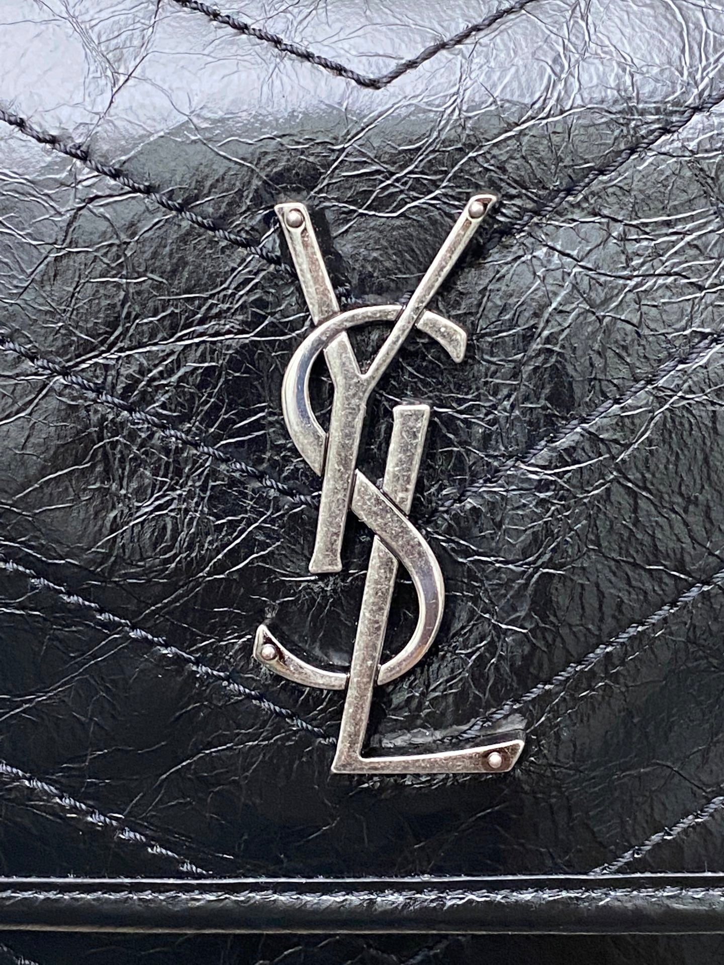 YSL metal logo on Saint Laurent quilted leather bag front