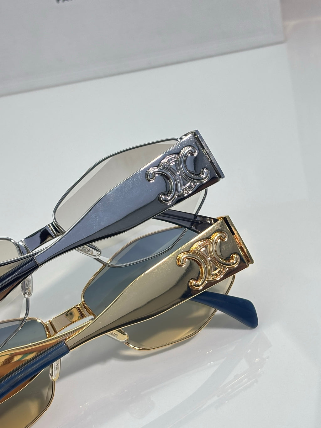 Close-up of sunglasses hinge with gold and silver details on blue temples