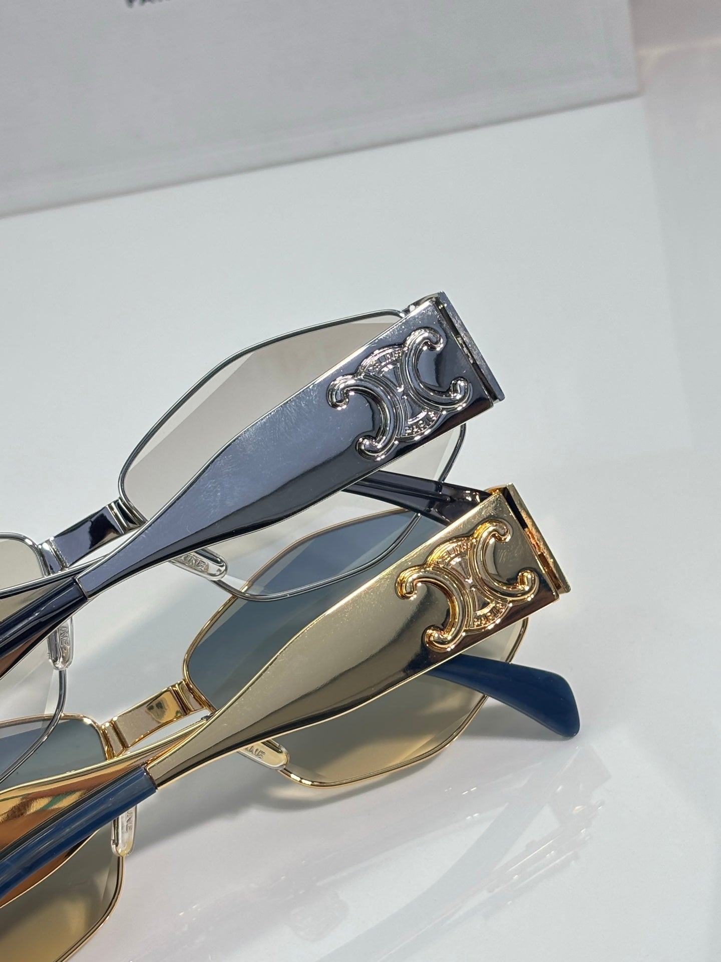 Close-up of sunglasses hinge with gold and silver details on blue temples